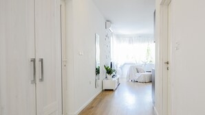 A hallway with wooden flooring, white walls, and a bed in the distance. - Deluxe Apartments Goya (Zadar)