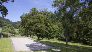 A rectangular outdoor area with a gravel surface, surrounded by grass and trees.