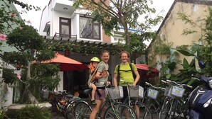A courtyard with bicycles, a child in a stroller, and a building with a balcony. - Bean Grass Homestay (Da Nang)
