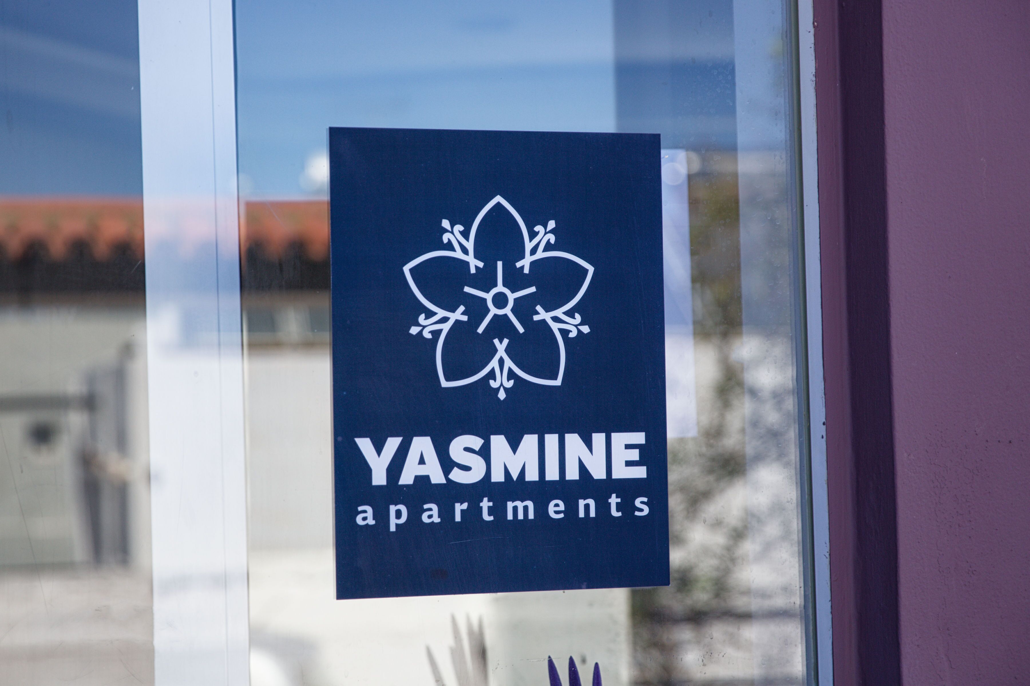 A sign for Yasmine apartments with a logo and text.