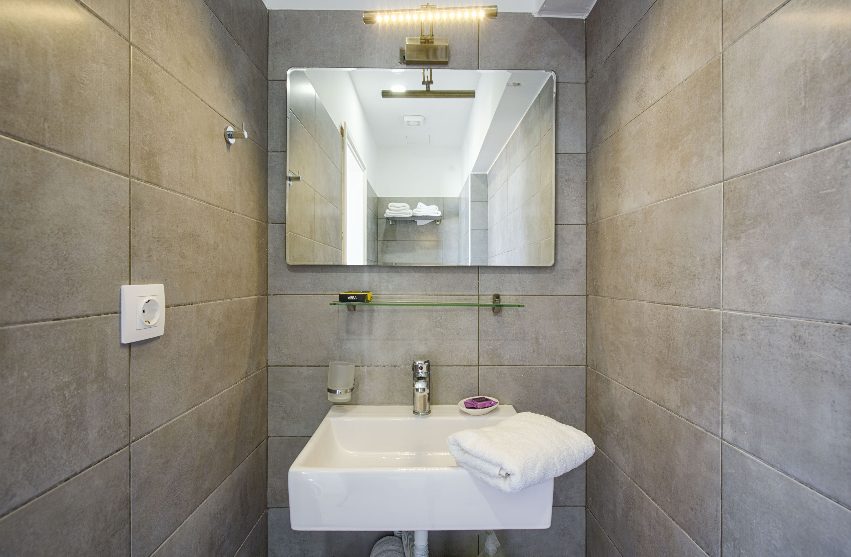 A modern bathroom with a large mirror, a white sink, and a towel rack.