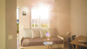 Una habitación acogedora con un sofá, una mesa de comedor y una ventana por donde entra la luz del sol.