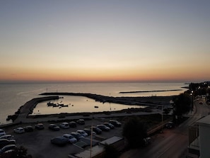 A coastal view with a marina, parked cars, and a road leading to a building with a sign reading "HISTORIC".