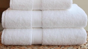 Une pile de serviettes blanches disposées en forme de pyramide sur une surface tissée.