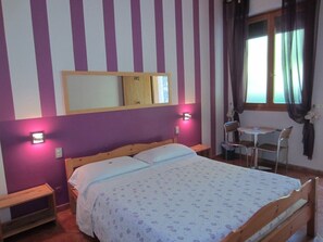 A bedroom with a bed, a small table, two chairs, a mirror, and a window with curtains. - Hotel Montemorello (Sesto Fiorentino)