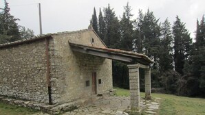 Un bâtiment rustique en pierre, doté d’une petite porte et d’une entrée pavée de pierres.