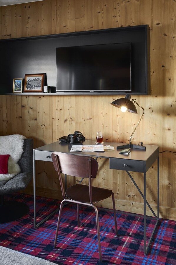 Una habitación con escritorio, silla y televisor montado en la pared.