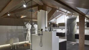 Un baño moderno con cabina de ducha de vidrio, lavamanos blanco y espejo.