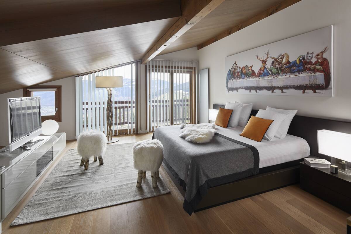A modern bedroom with a large bed, a television, and a painting of animals on the wall.