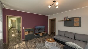 Een moderne woonkamer met een grijze bank, een televisie en een houten salontafel.