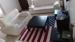 A living room with two white sofas, a black coffee table, and a TV on a stand. - Maurica Homes (Nairobi)