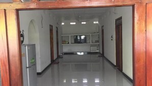 A corridor with a kitchen area at the end, featuring a refrigerator, microwave, and a small counter. - onelove hostel (Trincomalee)