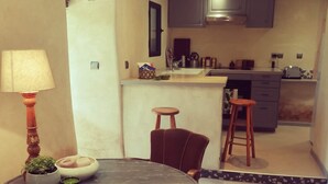 Uma cozinha moderna com uma ilha central, uma área de refeições com uma mesa redonda e um banquinho pequeno.