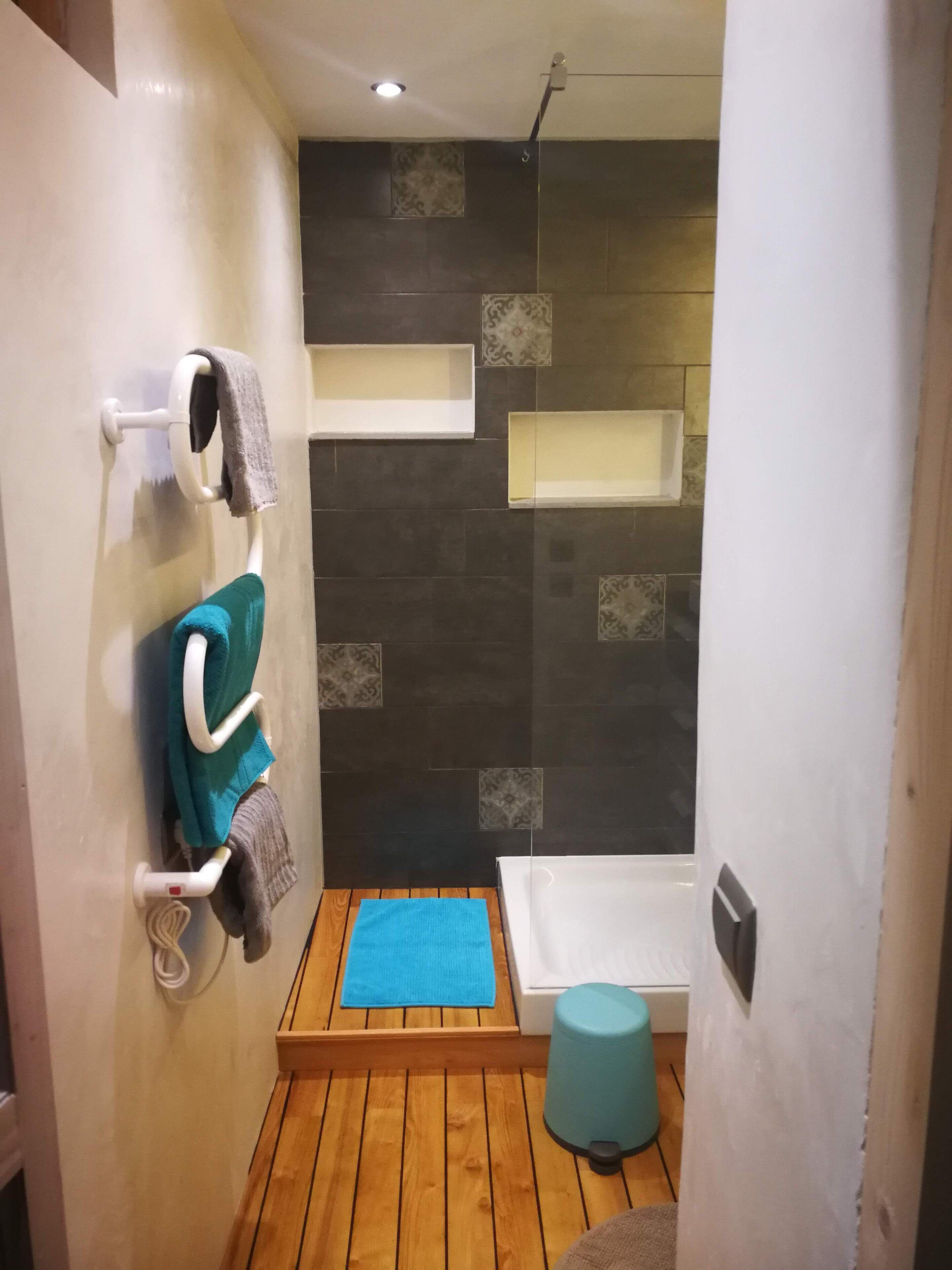 Une salle de bain moderne avec un plancher en bois, une baignoire, un espace douche et un porte-serviettes avec plusieurs serviettes.