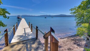 A wooden pier leading to a calm lake with boats, surrounded by trees and mountains in the background. - Anchors Aweigh - Lakefront - TLUXP (Tahoe City)