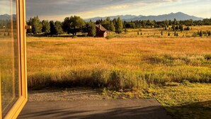 A view from inside a building looking out at a field with a small house and mountains in the distance. - Black Bear Ranch -Large home near Bozeman's Hyalite Canyon with peace & quiet (Bozeman)