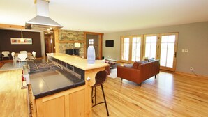 A spacious living area with a kitchen island, a dining table, and a seating area with a sofa. - Black Bear Ranch -Large home near Bozeman's Hyalite Canyon with peace & quiet (Bozeman)