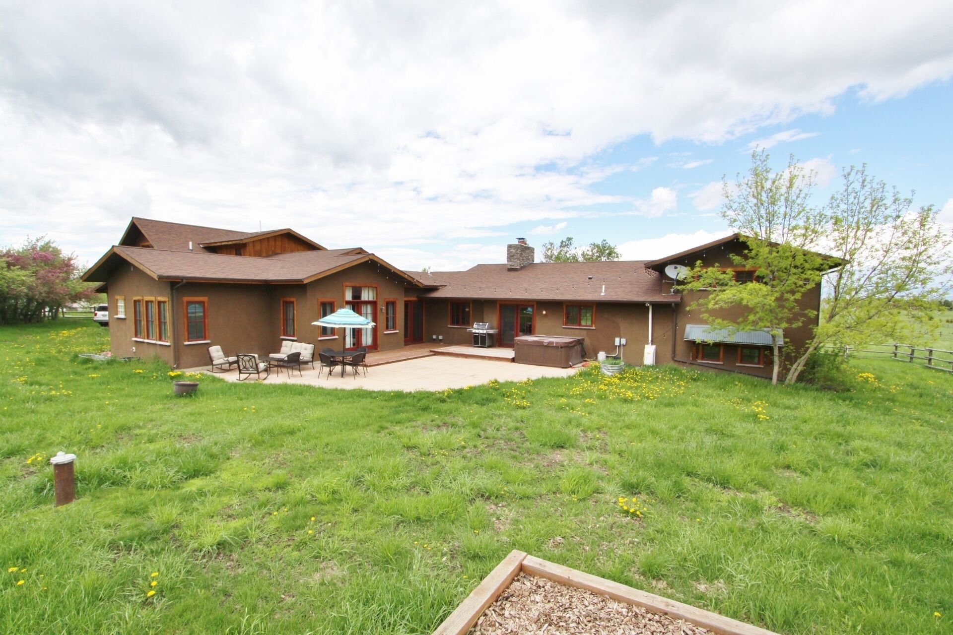 Una casa de dos pisos con un patio, mobiliario exterior y un jacuzzi.