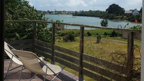 Un balcon donnant sur un lac, une chaise et une clôture en bois.