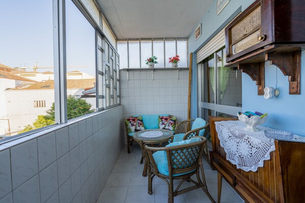 A balcony with wicker furniture, a small table, and a decorative bowl on a wooden cabinet.