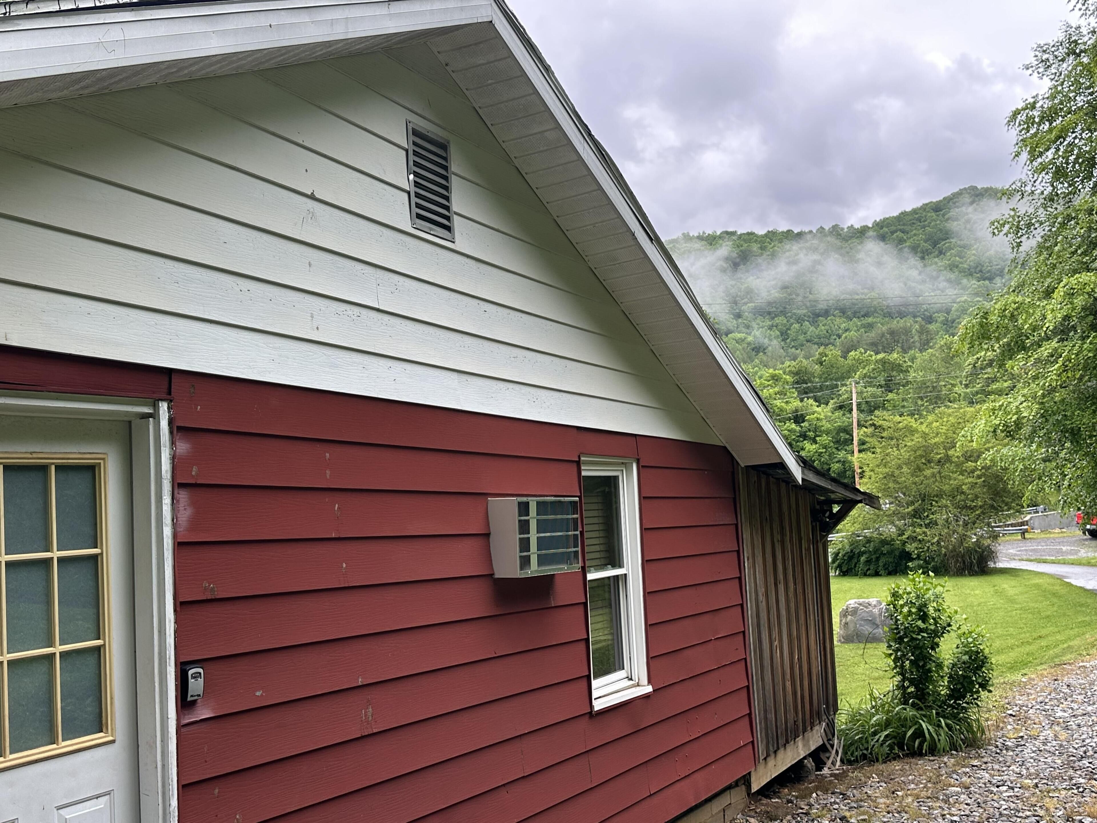 A red house with a white door, a small window, and a vent on the roof.