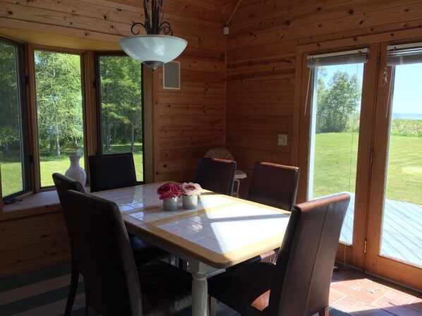Eine Holzhütte mit Esstisch, Stühlen und einer Vase mit Blumen.