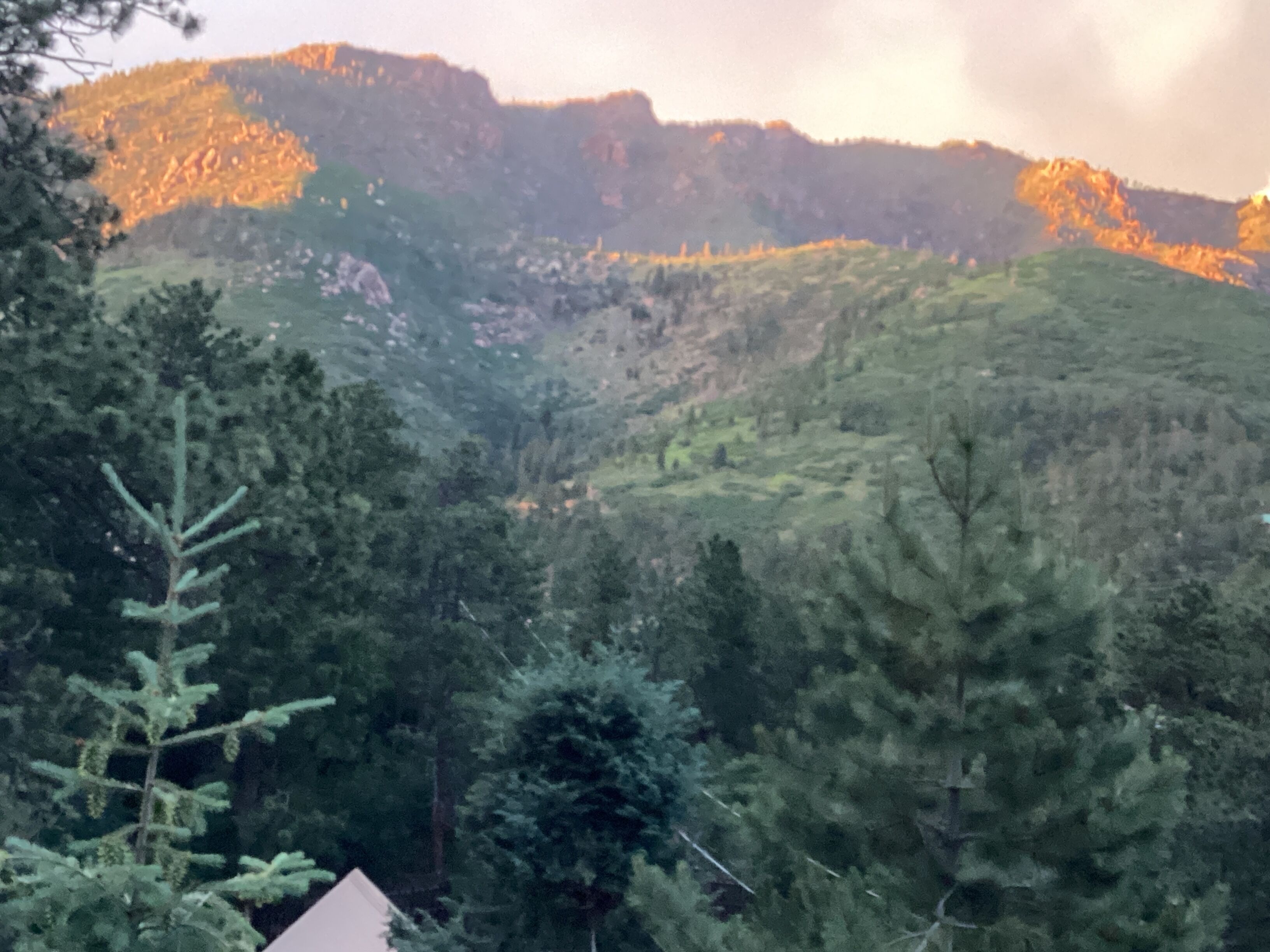 Paisagem montanhosa com floresta densa e um pequeno edifício.
