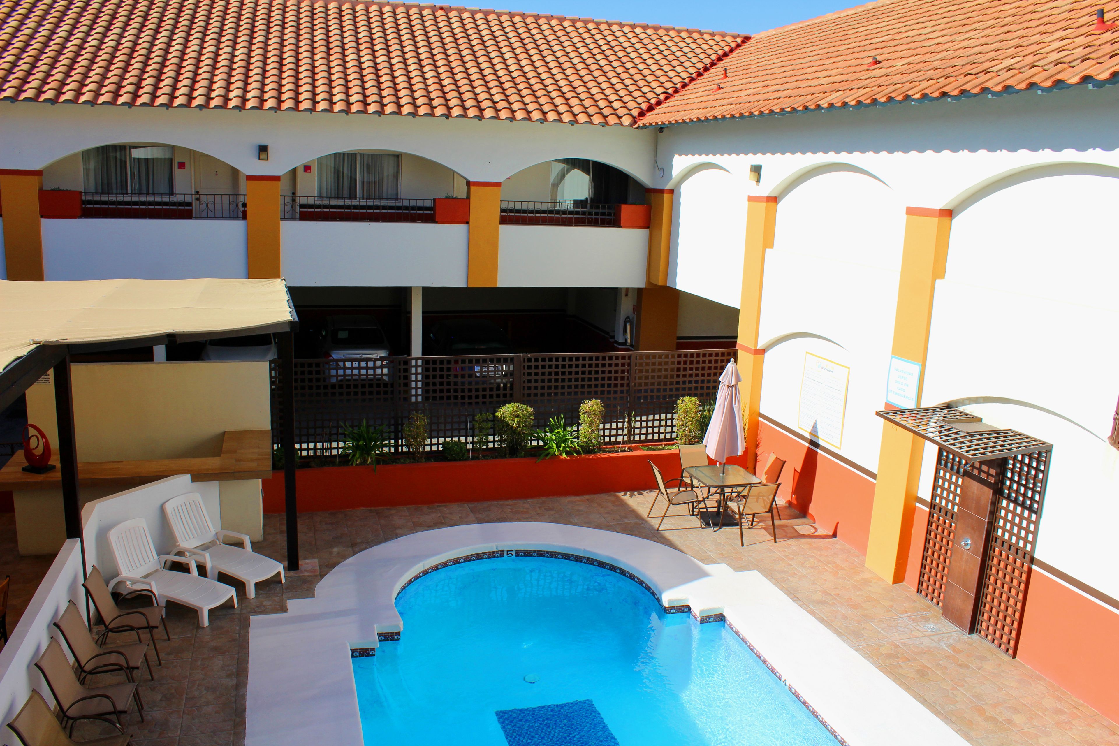 Una piscina con sillas de descanso y una zona de estar techada.