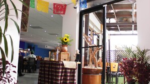 A hotel lobby with colorful paper decorations hanging from the ceiling, a reception desk, and potted plants. - Del Mar Inn Playas de Tijuana (Tijuana)