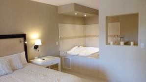 A hotel room with a bed, a bedside table with a lamp, a bathroom with a bathtub, and a mirror. - Del Mar Inn Playas de Tijuana (Tijuana)
