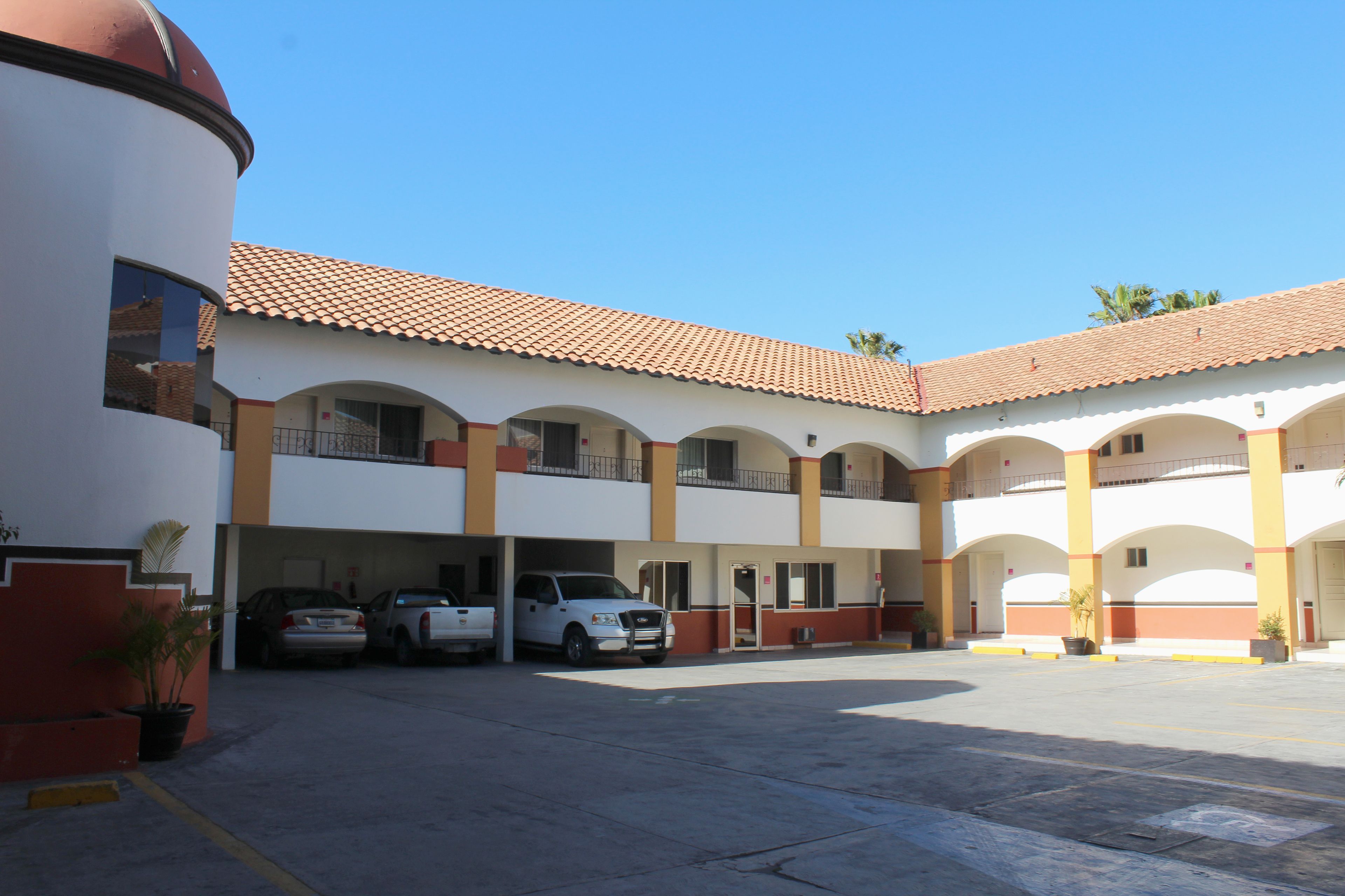 A multi-story building with a parking area, featuring a central courtyard and multiple balconies.