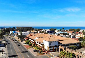 Un hotel con tejado de baldosas, un letrero llamativo y vistas al mar.