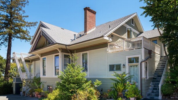 Ein zweistöckiges Haus mit Veranda, Treppe und einem Ziegelkamin.
