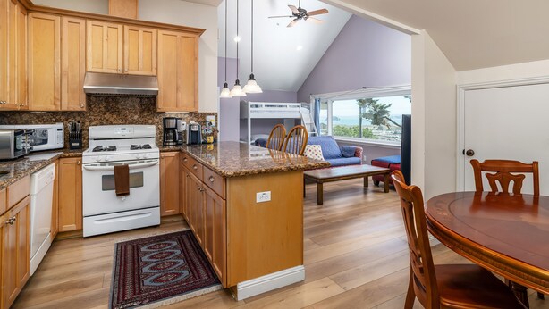 A kitchen with wooden cabinets, a stove, and a dining area with a table and chairs.