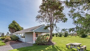 A small, single-story house with a sloped roof, a front porch, and a well-maintained lawn.