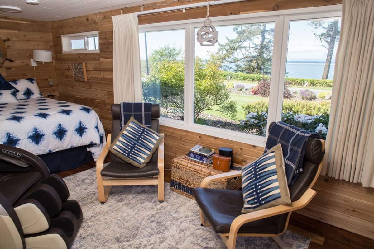 A cozy room with a bed, two chairs, a massage chair, and a view of the outdoors.