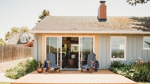 Una casa con terraza, dos sillas Adirondack y una chimenea.