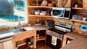 A compact kitchen with wooden cabinetry, a stainless steel stove, and a microwave.
