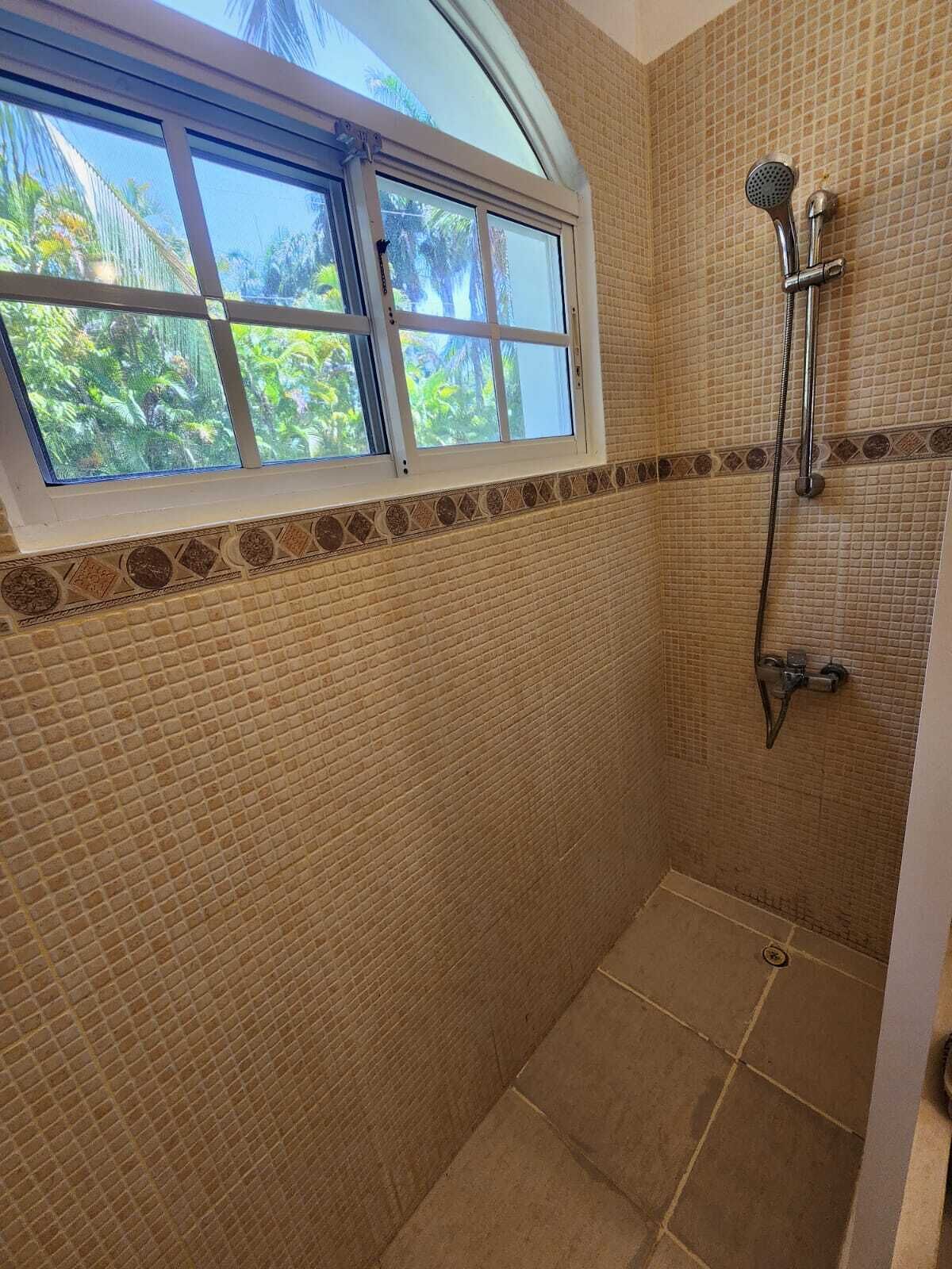 Eine Dusche mit Fenster, gefliesten Wänden und einer Duschbrause.