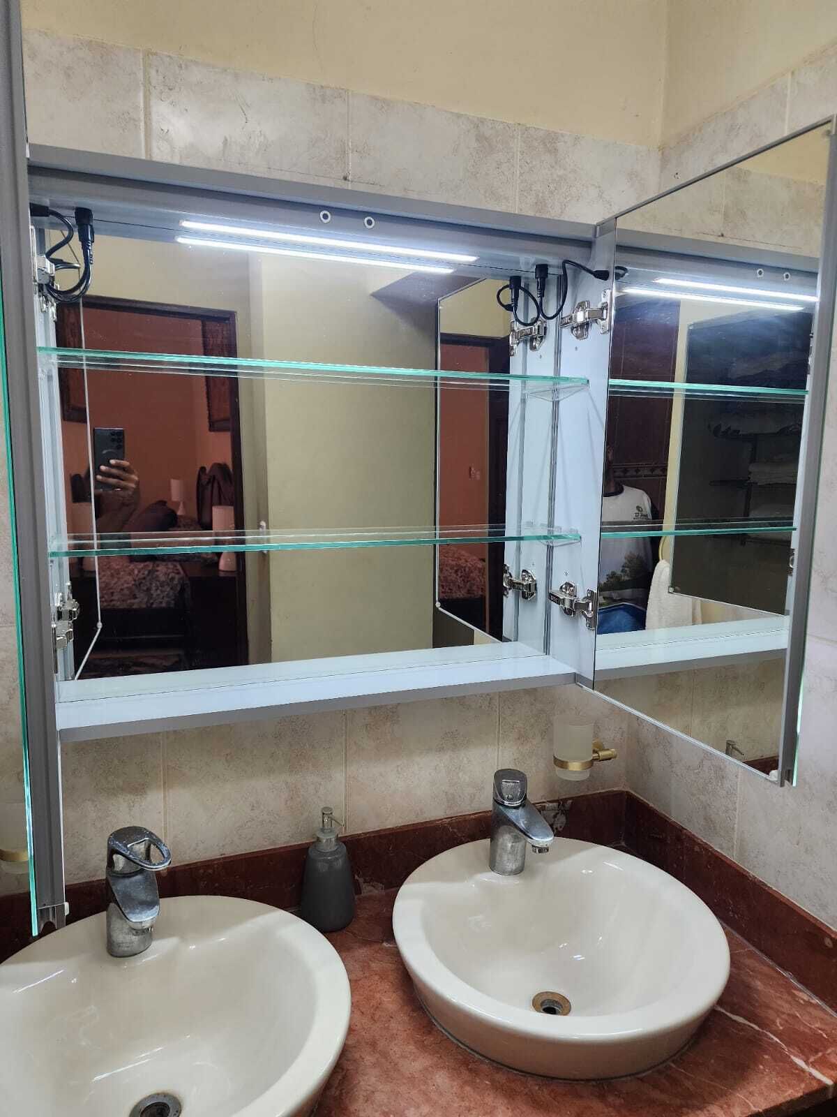 Een badkamer met twee wastafels, een grote spiegel en een glazen scheidingswand.