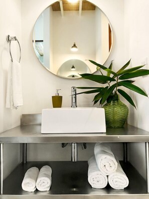 A bathroom with a round mirror, a white sink, a green plant, and towels. - ★Luxury Apartment in Gated Eco-Community. 1min walk to the Beach★ (Santa Teresa Beach)