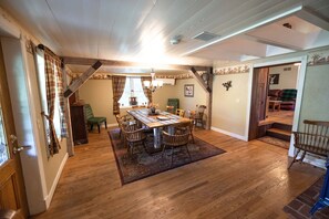 Enjoy meals in this cozy dining area with a wooden table and six chairs, surrounded by exposed beams and a chandelier.