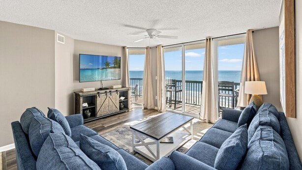 A spacious living room with a large flat-screen TV, a sofa set, a coffee table, and a balcony with a view of the ocean. - Amazing 8th Floor Condo, Clean, Sleeps 10, Near Main St. | AshWorth - 801 (North Myrtle Beach)