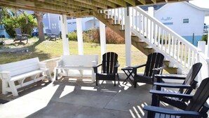 An outdoor patio with white and black Adirondack chairs, a white bench, and a staircase leading to a covered area. - Steps to Beach 2BR 2BA duplex (Atlantic Beach)