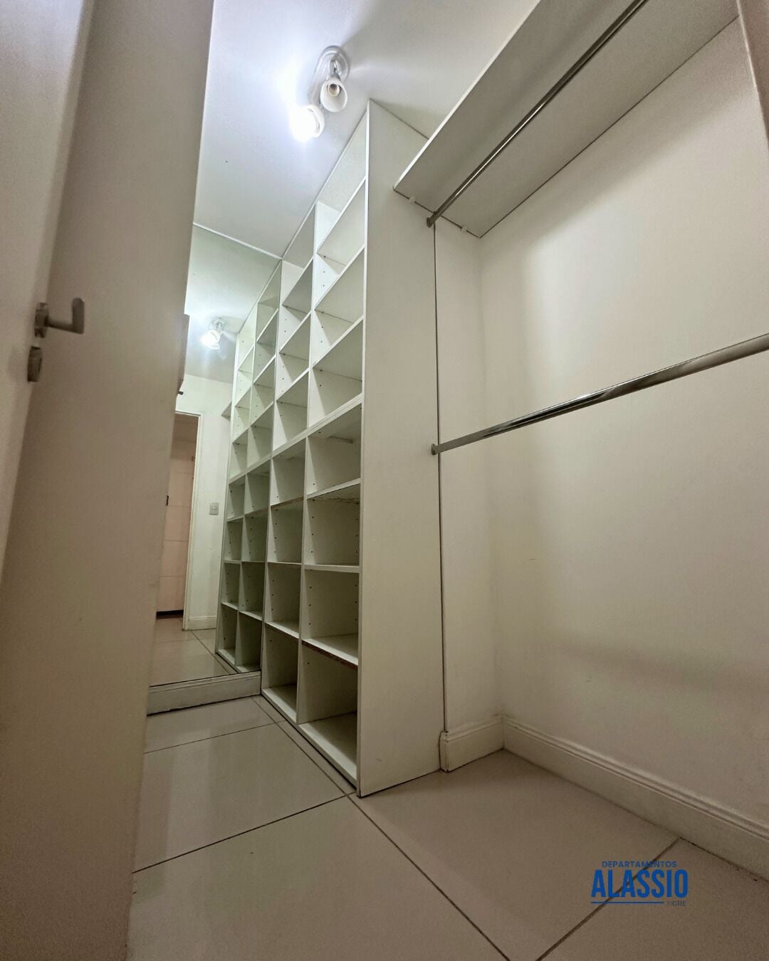 Un couloir avec un placard blanc et des étagères.