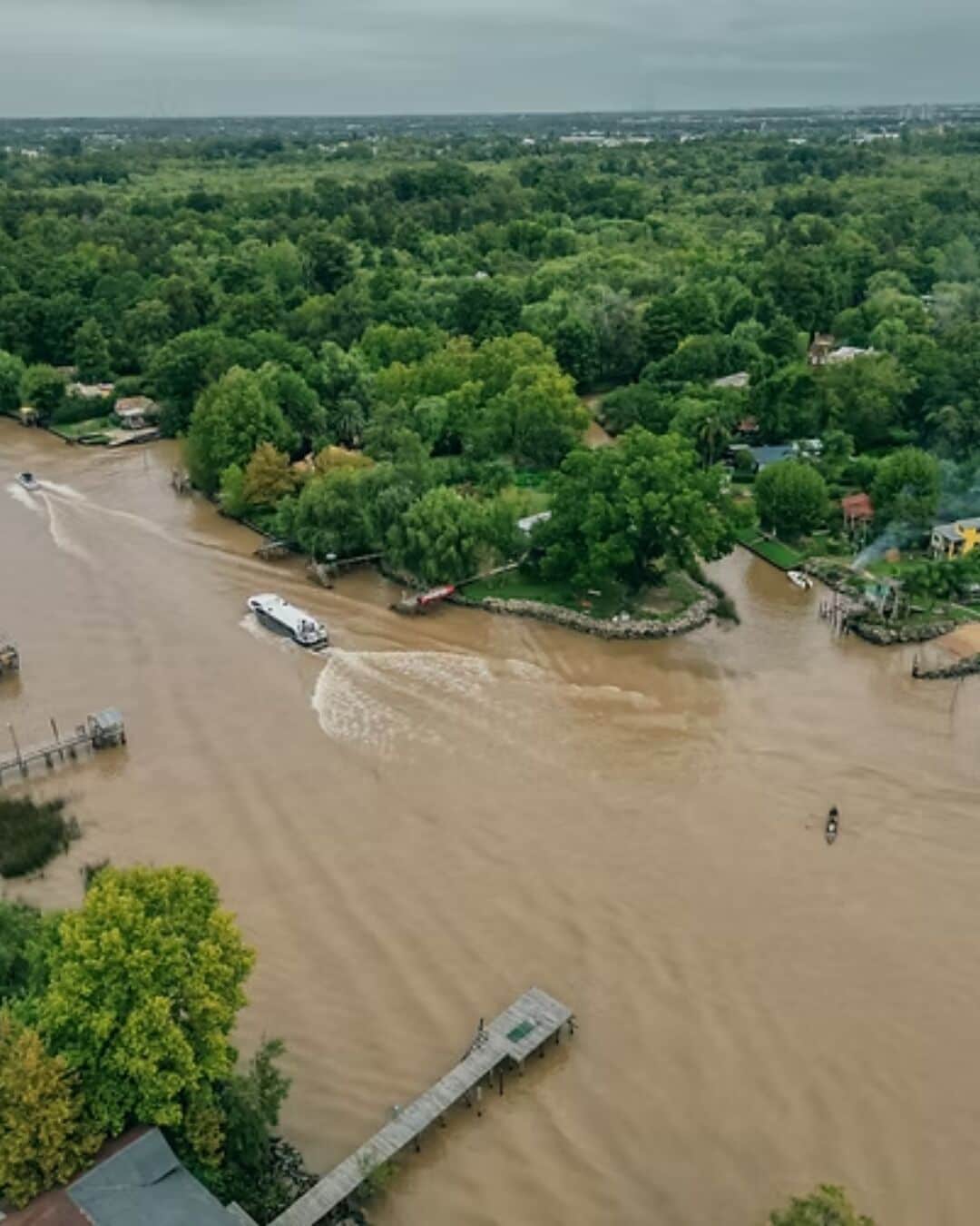 Un río que atraviesa una zona boscosa densa con un puente y un muelle.
