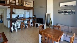 A spacious living area with a dining table, kitchen, and a balcony. - Departamento Alassio (Tigre)