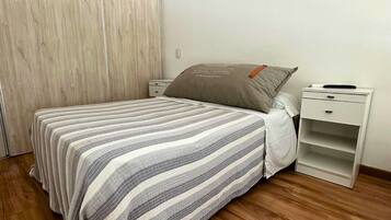 Un dormitorio con cama, mesita de noche, armario y suelo de madera.