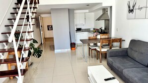 A modern living room with a staircase, a dining area, and a kitchen. - Departamento Alassio (Tigre)