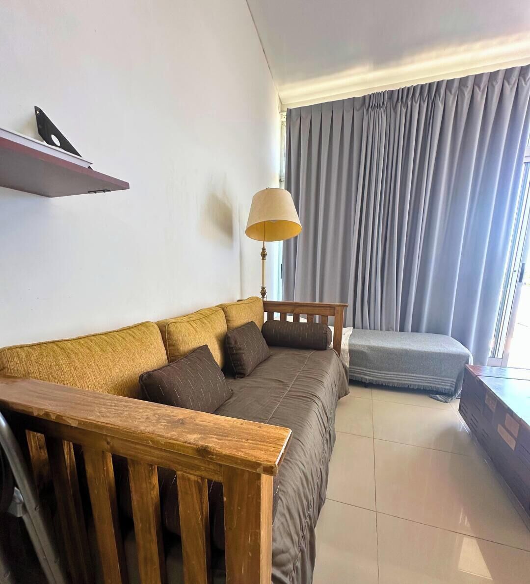 Una sala de estar moderna con un sofá, una mesita de madera, una lámpara y un ventanal con cortinas.